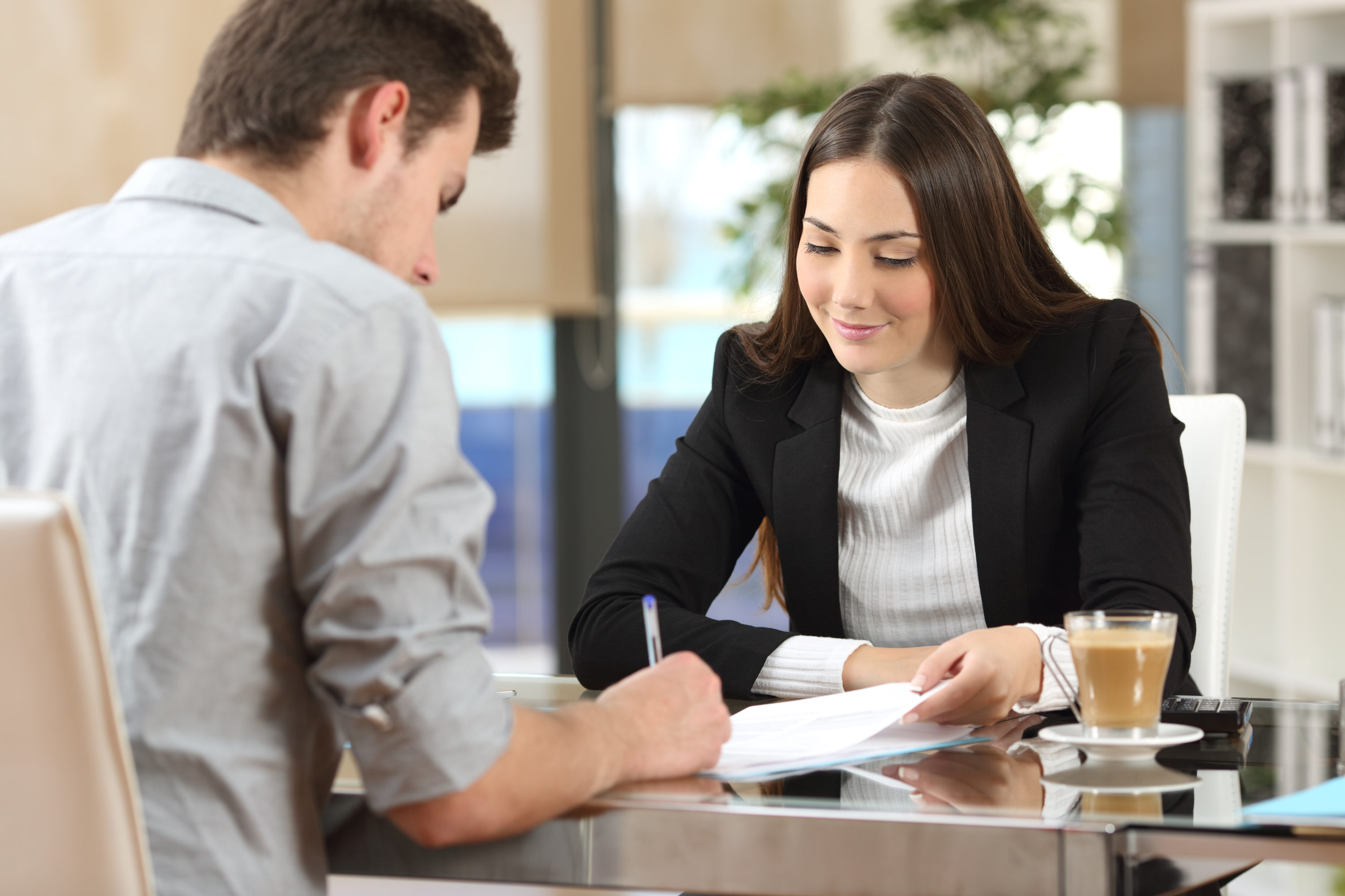 A man signing a commercial insurance policy while the insurance broker watches